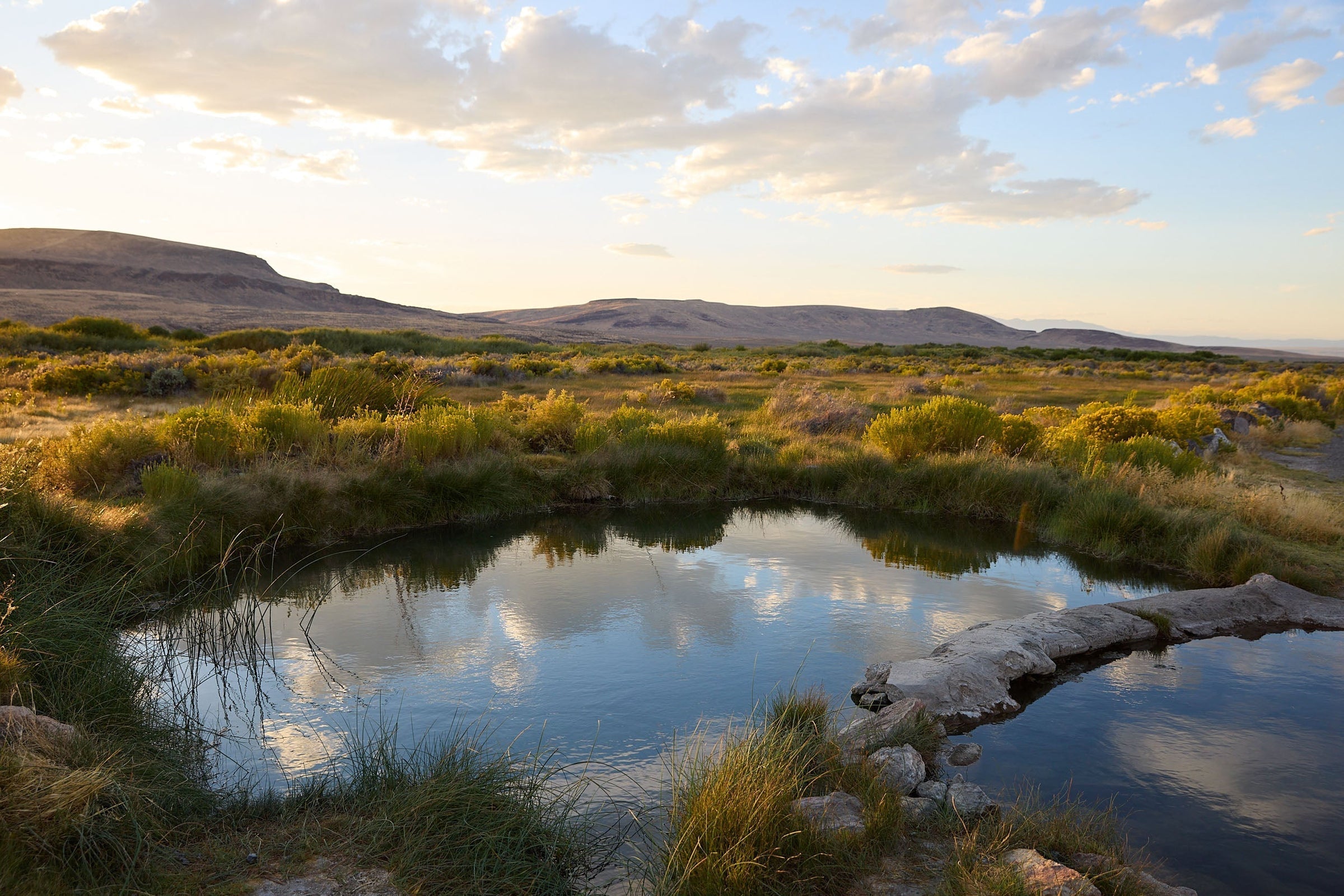 A picturesque nature scene with water, greenery, and a sky with minimal clouds.