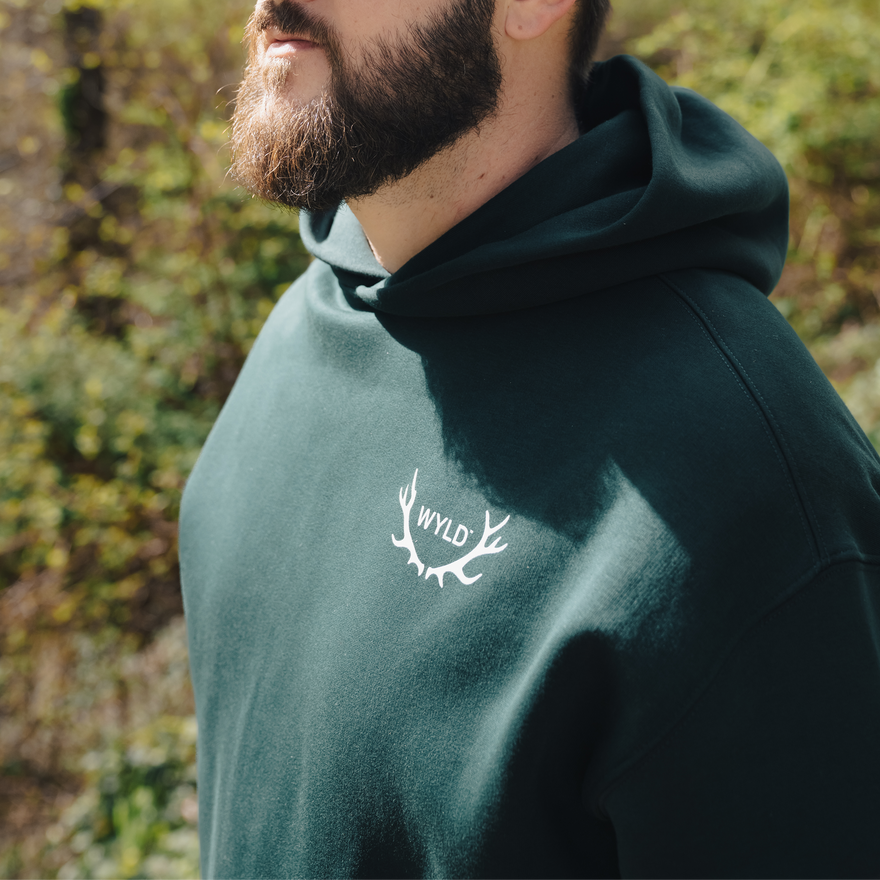 Man wearing a green hoodie with 'WYLD' logo outdoors